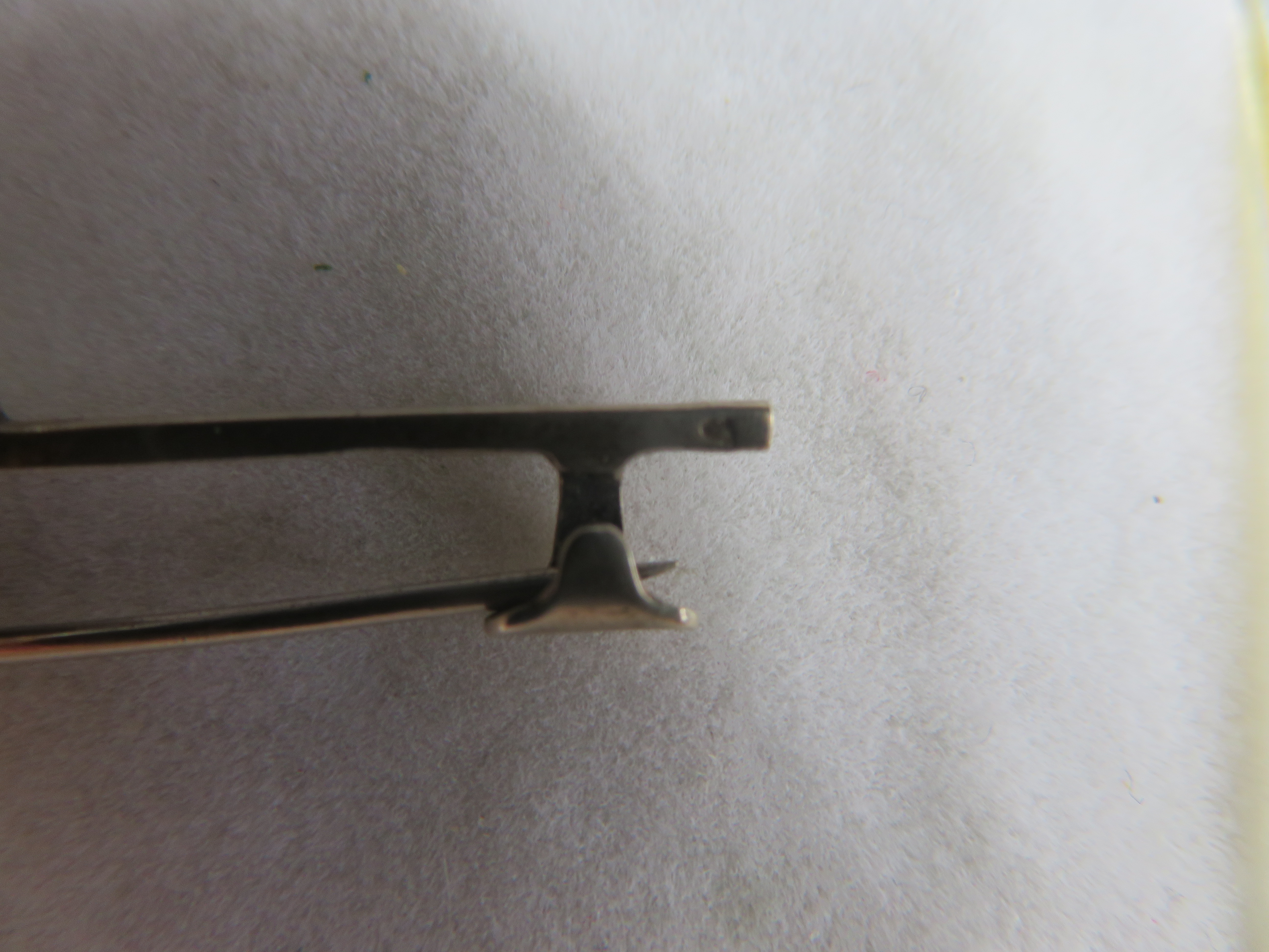 Verzilverde langwerpige broche met blauwe steen