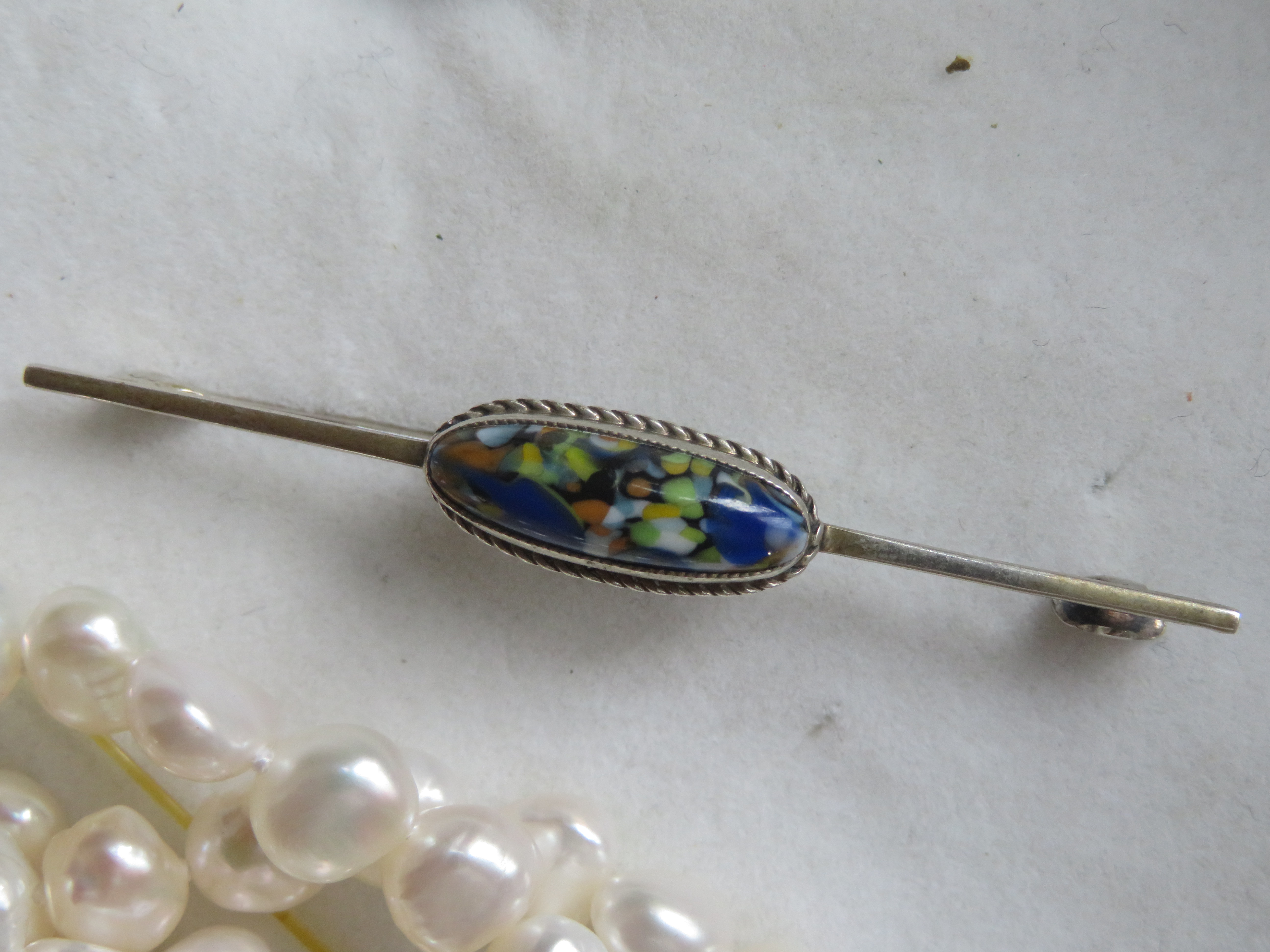 Verzilverde langwerpige broche met blauwe steen