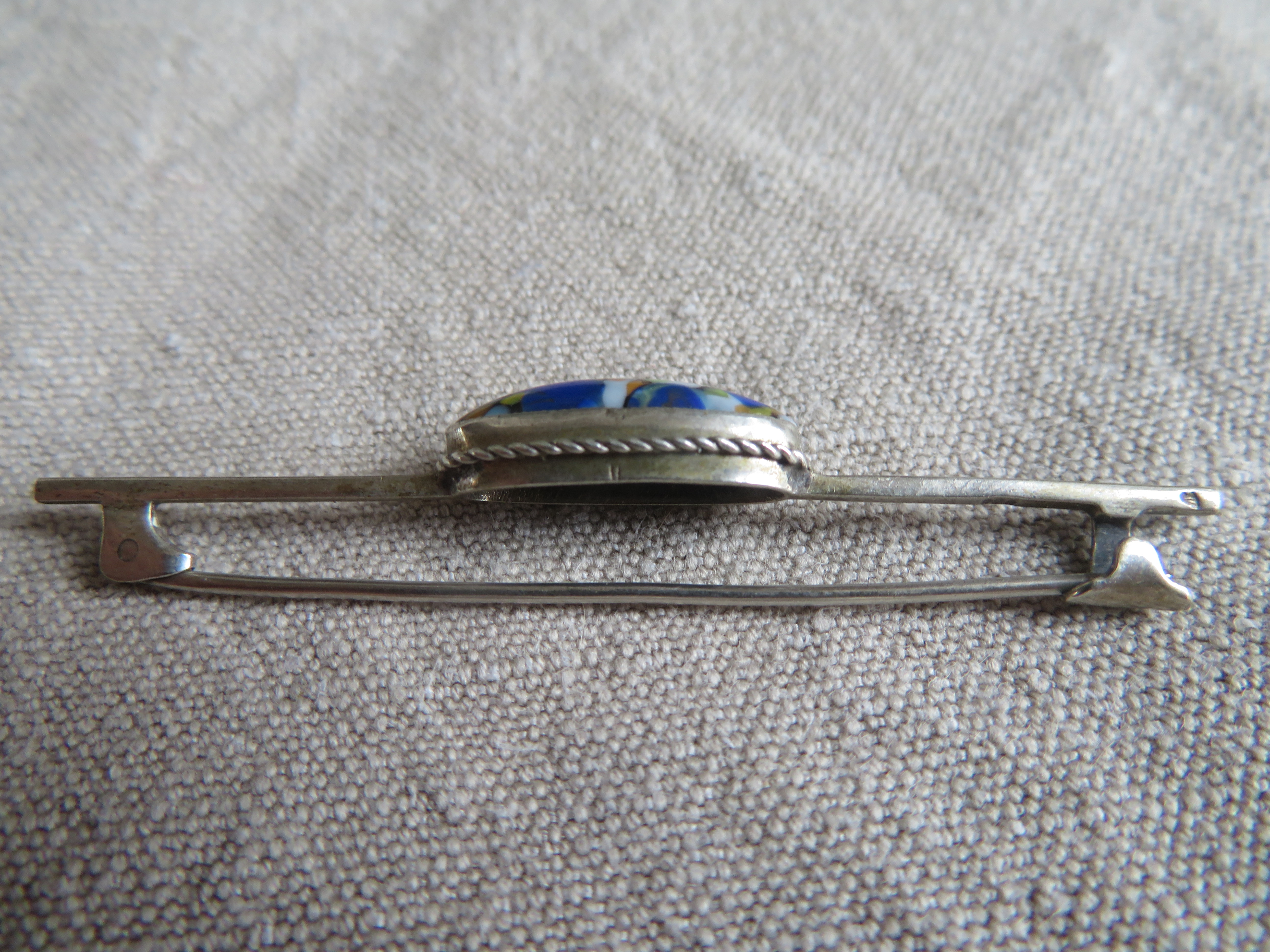 Verzilverde langwerpige broche met blauwe steen
