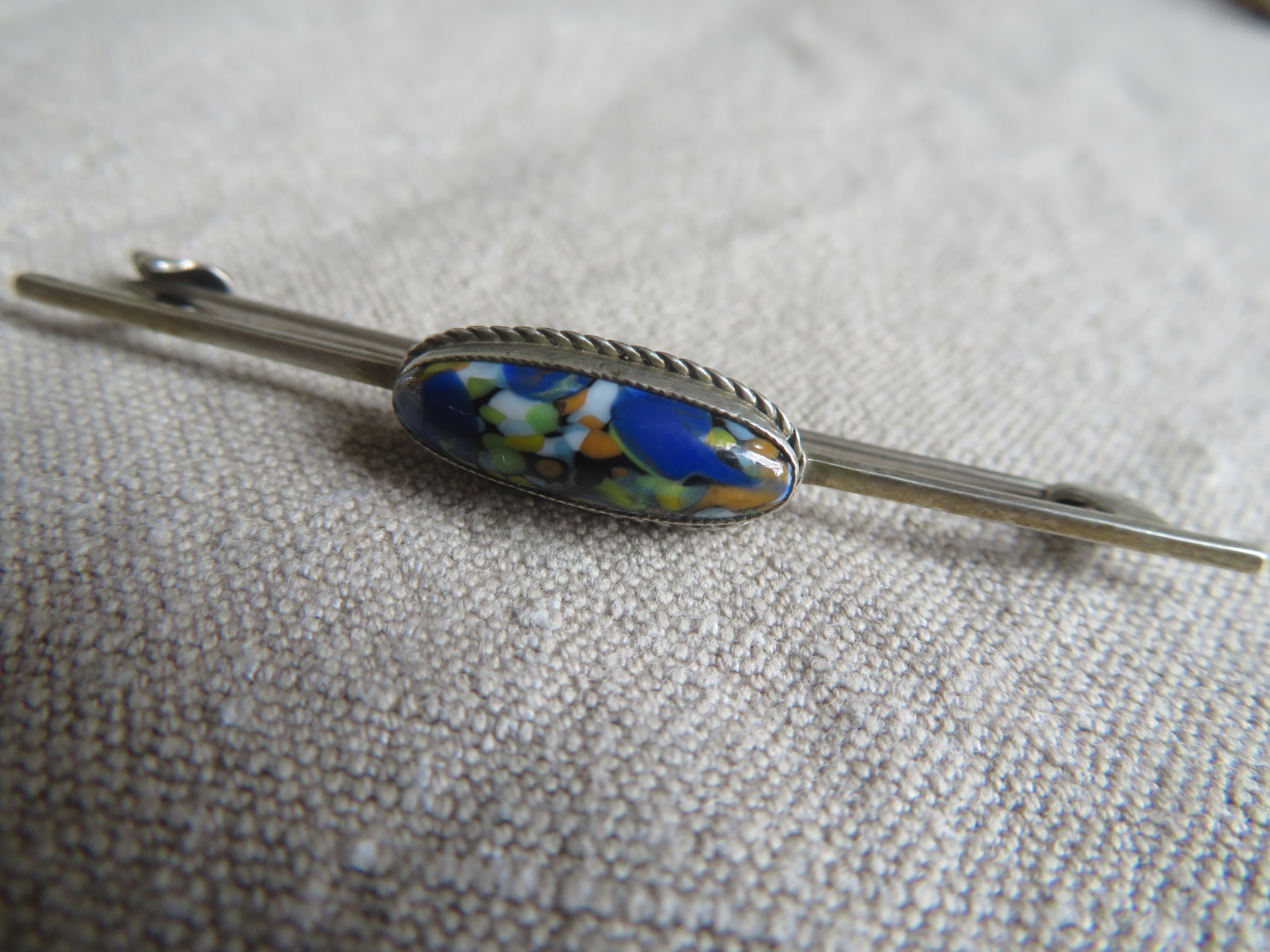 Verzilverde langwerpige broche met blauwe steen