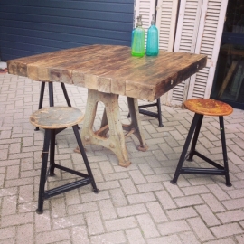 Tafel met gietijzeren onderstel en dik ruw houten blad.