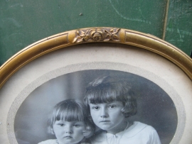 Brocante goudkleurige ovale lijst met glas en oude foto.