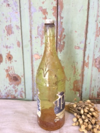 Oude limonadefles merk Whip met een gele vloeistof.