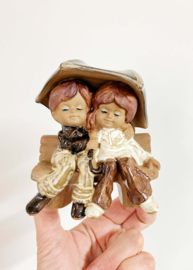 Keramieken vintage beeldje van een jongen en een meisje onder een paraplu.