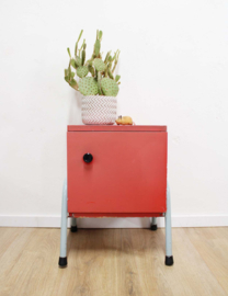 Rozig rood retro nachtkastje. Houten vintage kastje op metalen poten
