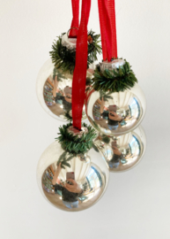 Vier zilveren kerstballen aan rood lint. Vintage kerstdecoratie.