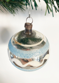Zilveren glazen vintage kerstbal met licht blauwe streepjes.