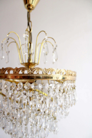Goudkleurige kroonluchter met pegels in swirl. Hollywood Regency hanglamp