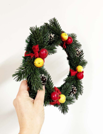 Vintage kerstkrans met dennenappels, fruit en rode linten. Retro kerstversiering