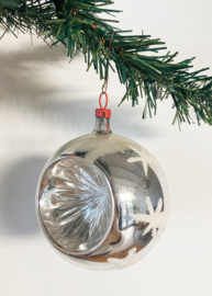 Zilveren deukbal met sterren. Glazen retro kerstbal met rood dopje