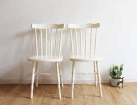 Twee houten retro stoelen. Set witte vintage spijlenstoelen.
