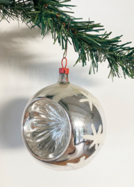 Zilveren deukbal met sterren. Glazen retro kerstbal met rood dopje