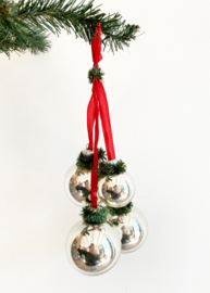 Vier zilveren kerstballen aan rood lint. Vintage kerstdecoratie.