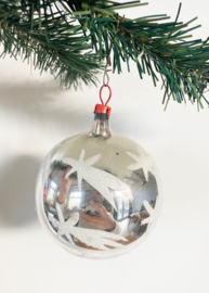 Zilveren deukbal met sterren. Glazen retro kerstbal met rood dopje