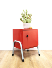 Rozig rood retro nachtkastje. Houten vintage kastje op metalen poten