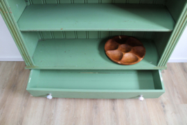 Goene vintage boekenkast. Houten keukenkast met planken en lade