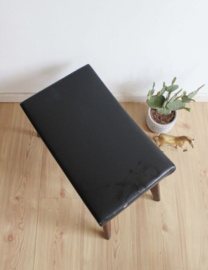 Vintage voetenbankje met zwarte bekleding. Houten retro kruk/luiwammes