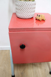Rozig rood retro nachtkastje. Houten vintage kastje op metalen poten