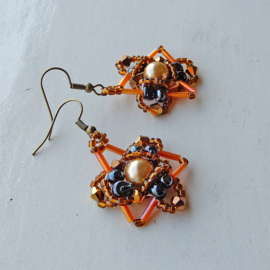 Goudkleurige parel met zwarte glaskralen, kristallen en oranje staafjes aan haken van brons