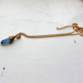 Blauw kristal in gouddraad gewikkeld aan een goudkleurige ketting