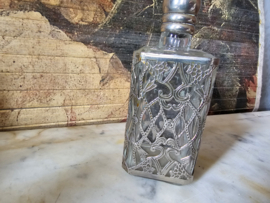 Oud glazen flesje in zilverkleurige houder