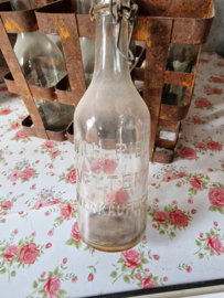 Oud flessenrek gevuld met glazen beugelflesjes