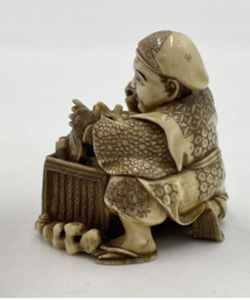 Antieke Netsuké van ivoor " welvarende koopman met mand vol koopwaar"