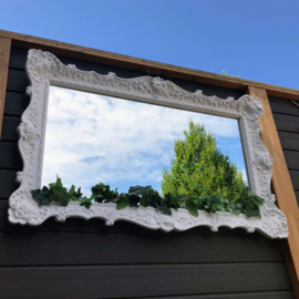 Te huur:   grote spiegel met brocante witte rand en plantdecoratie