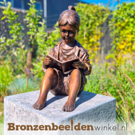 Beeld voor in de tuin van een lezend meisje