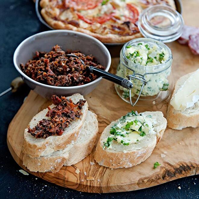 tapenade en brood geserveerd op een olijfhouten borrelplank