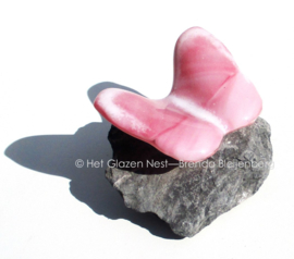 Roze vlinder met witte accenten op steentje