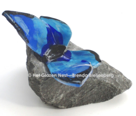 Blauwe glazen vlinder op grijze steen