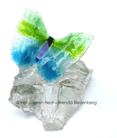 Speels groen en aqua vlinder op doorzichtig glasbrok