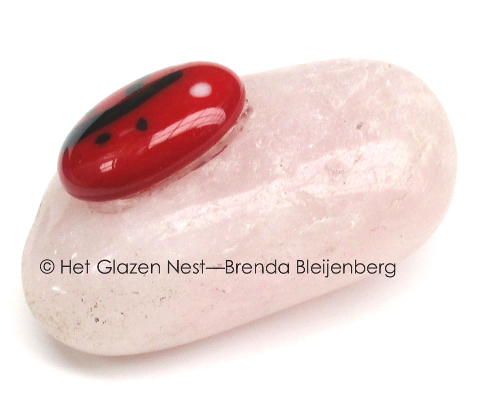 Glazen lieveheersbeestje op calciet knuffelsteen