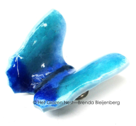 Kleine speelse vlinder in groenblauw glas