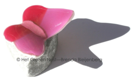 Kleine roze glazen vlinder op steentje