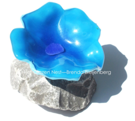 speelse abstract bloem in aqua blauw glas op steen