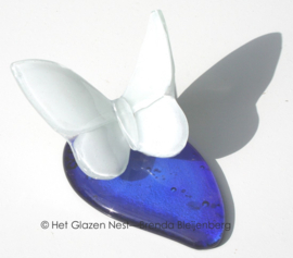 Witte vlinder op blauwe druppel van glas