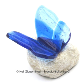 Blauw vlindertje van glas op witte steen