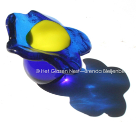 Kleine blauwe bloem op blauw glazen bolletje