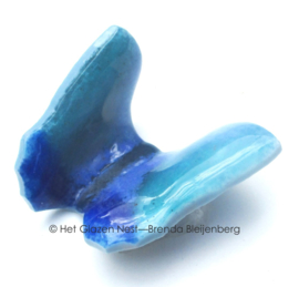 Kleine speelse vlinder in groenblauw glas