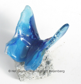 Blauwe vlinder van glas op steentje