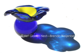 Kleine blauwe bloem op blauw glazen bolletje