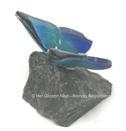 Glazen vlinder op basalt steen