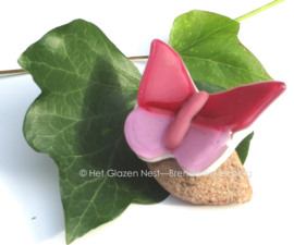 Kleine roze glasvlinder op steentje