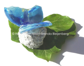 Blauwe vlinder van glas op steentje