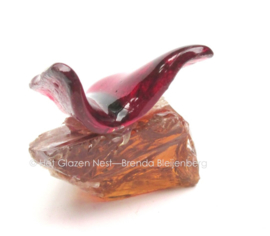 Kleine rode vlinder op ruw amberkleur glas