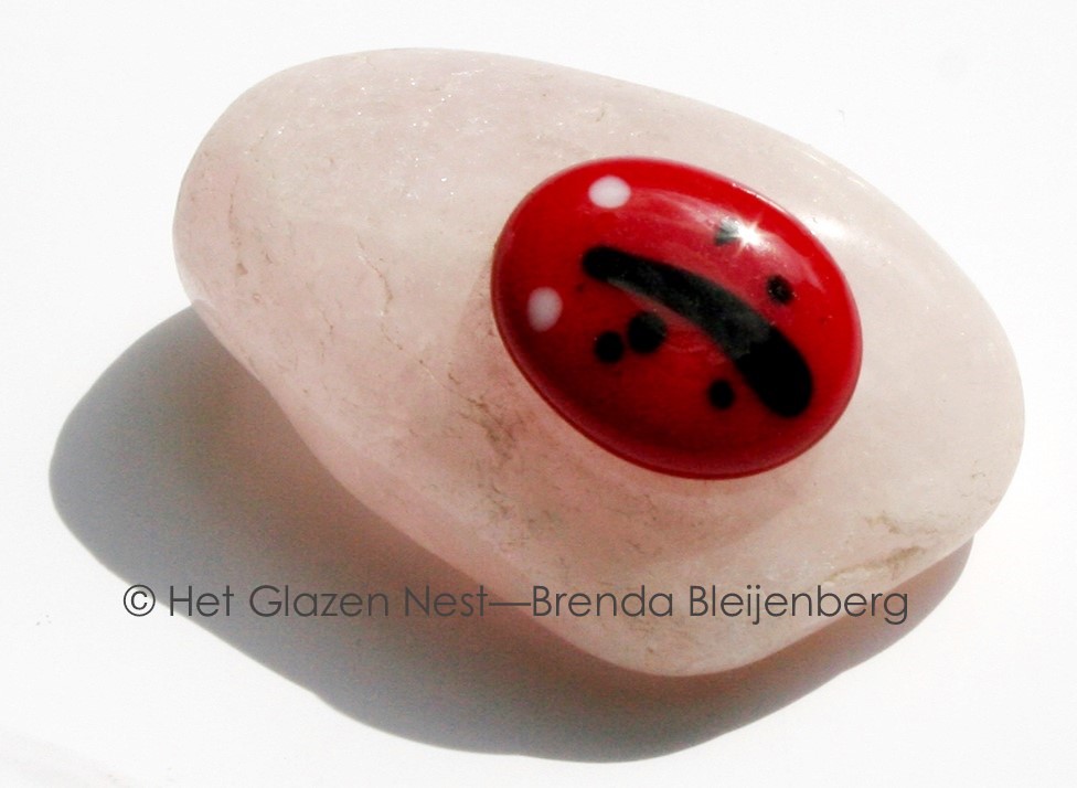 Glazen lieveheersbeestje op calciet knuffelsteen