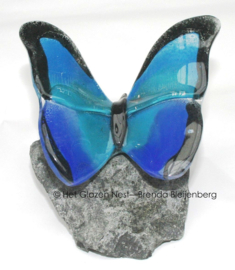 Glazen vlinder op basalt steen