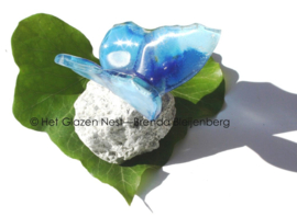 Blauwe vlinder van glas op steentje